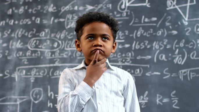 小男孩站在黑板前思考问题