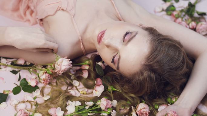 美丽的女孩躺在玫瑰里