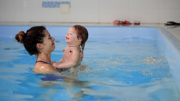 婴儿跳出泳池中游向母亲