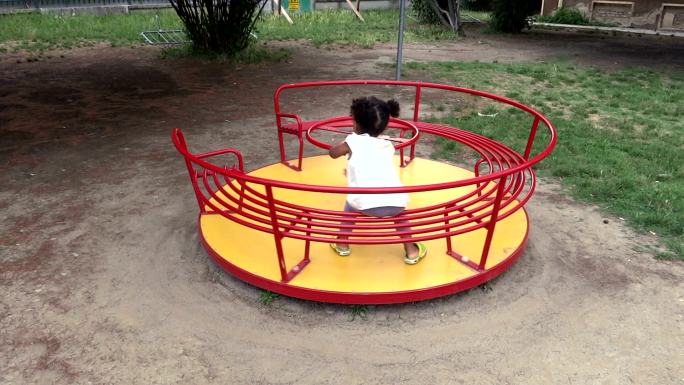 小女孩独自在儿童公园里荡旋转木马