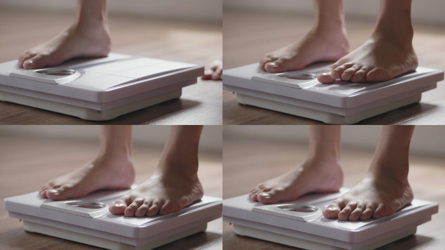 一位年轻的女子在家里用体重秤检查体重。