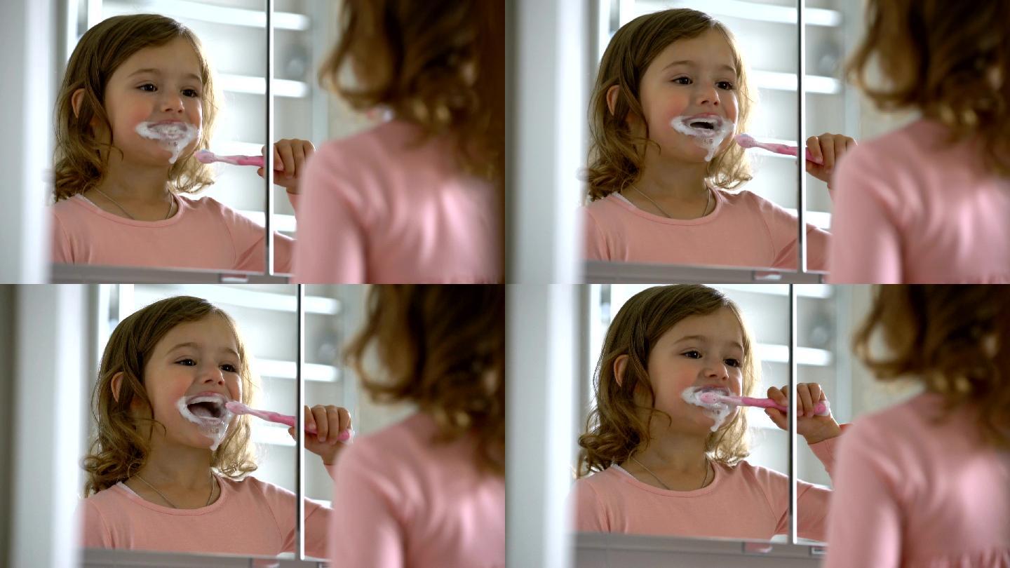 小女孩努力地对着镜子刷牙。
