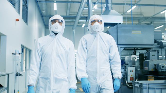 两名工程师穿着防毒服穿过技术先进的工厂