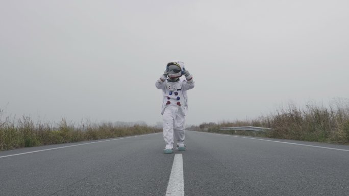 一名穿着宇航员服装的男子在公路上行走