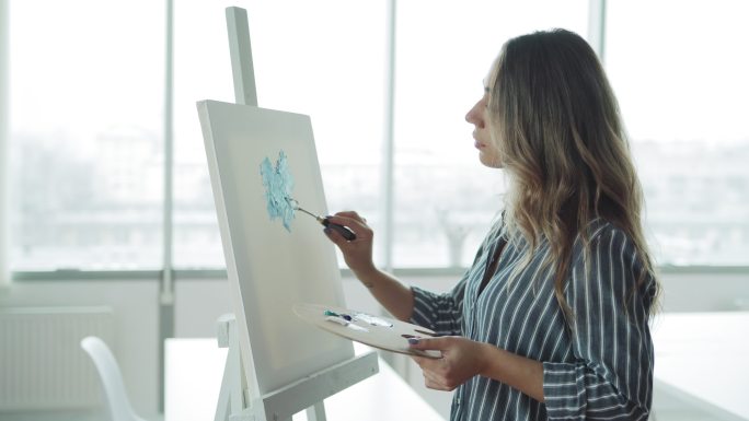 女艺术家站在画架旁绘画