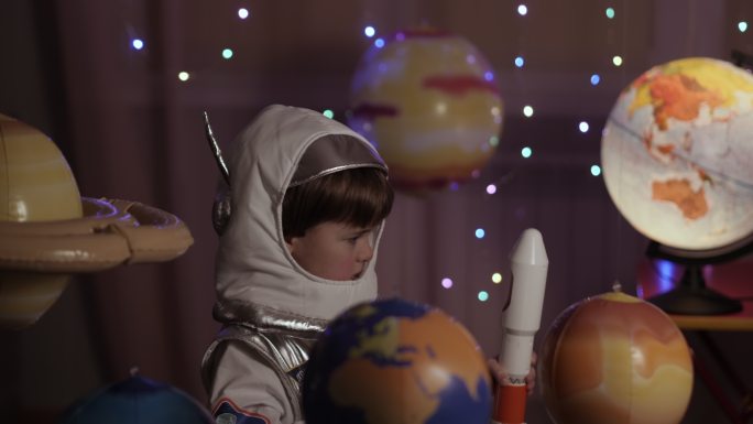 儿童梦想家玩着在行星间飞行的玩具