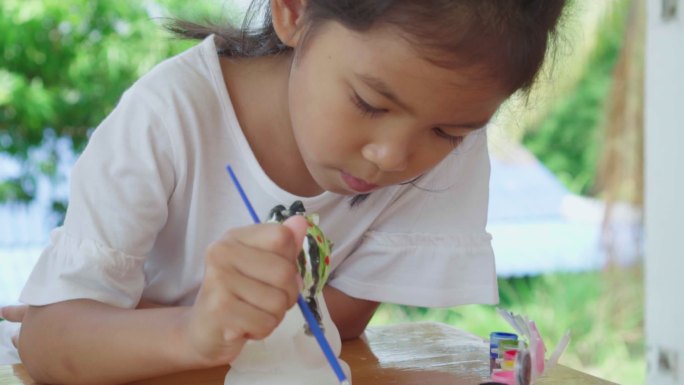 小女孩专注于用画笔给石膏像上色