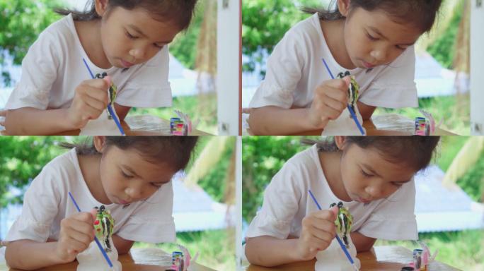 小女孩专注于用画笔给石膏像上色