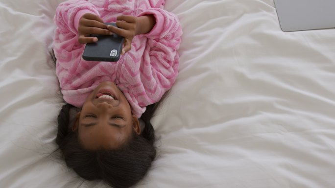 女孩穿着睡衣躺在床上玩手机