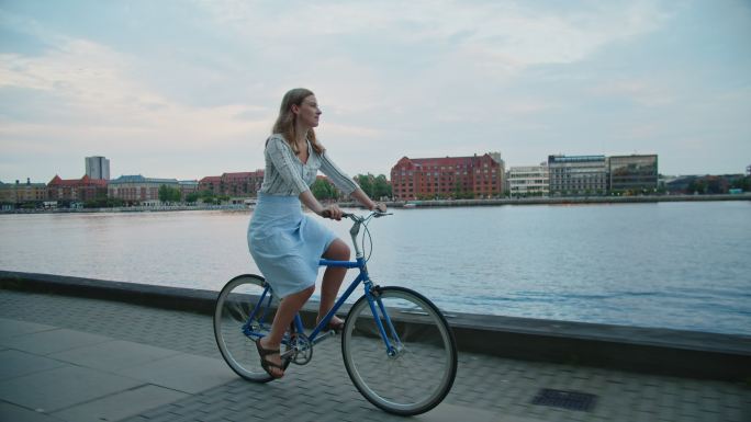 在城市滨水区骑自行车的女人