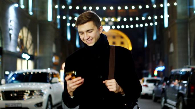 男子收到短信下班步行都市街道夜景