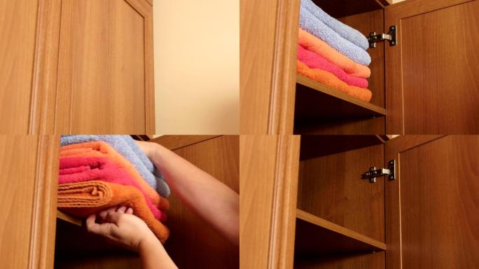 女人从衣柜的架子上拿出一堆的浴巾