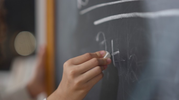 女学生用粉笔在黑板上写字
