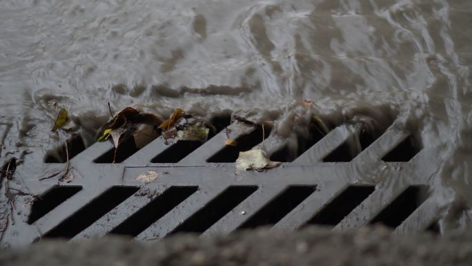 雨水和泥石流顺着街道边的雨水沟流下