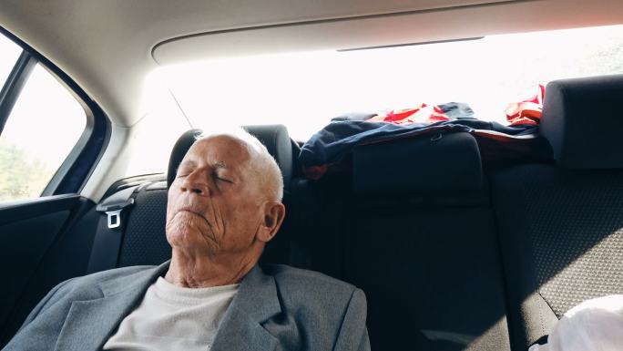 疲惫的祖父睡在汽车后座上