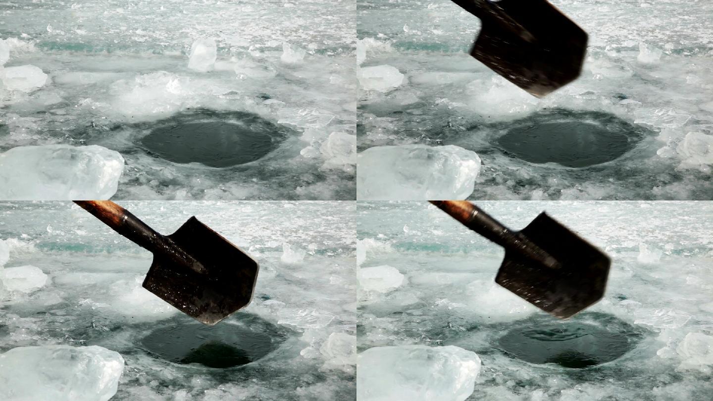 男人用铲子在冰上砍了一个洞