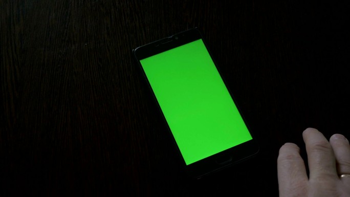 使用一部放在桌上的绿色屏幕智能手机