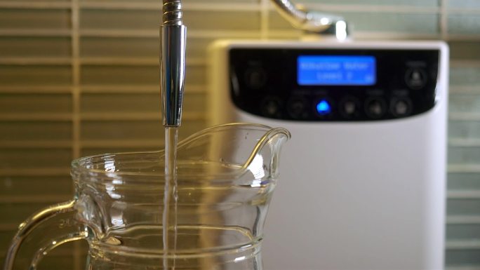 碱性水从净水机倒入玻璃罐中