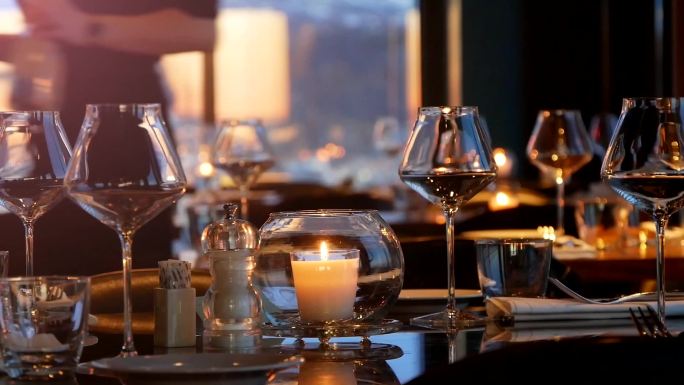 一家餐厅的桌子上摆着玻璃杯和蜡烛