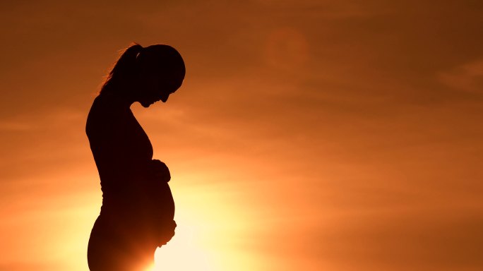 日落时美丽的孕妇孕妇肚子月子中心胎教母婴