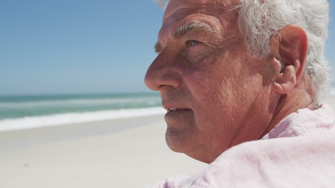 体贴的高加索老人坐在海滩上