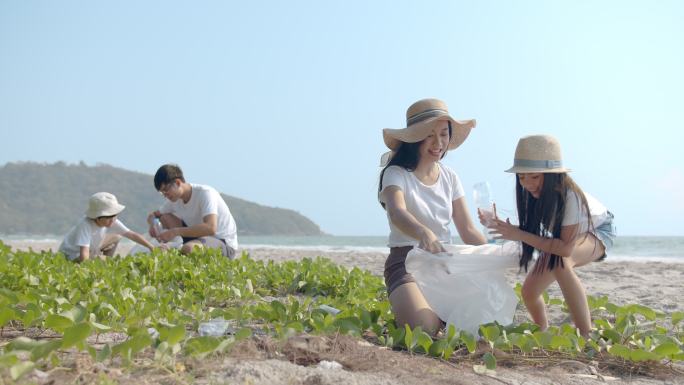 一个家庭在户外海滩上捡起塑料瓶扔进垃圾袋