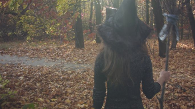 万圣节打扮的女巫在秋天的森林里休息。