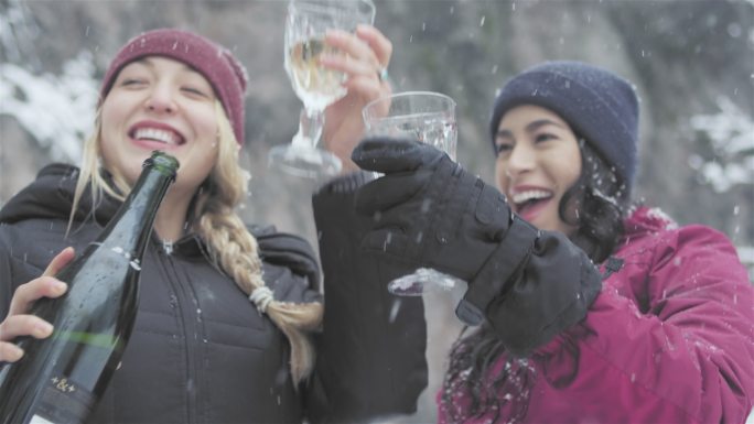 美丽的年轻女士在下雪天喝香槟