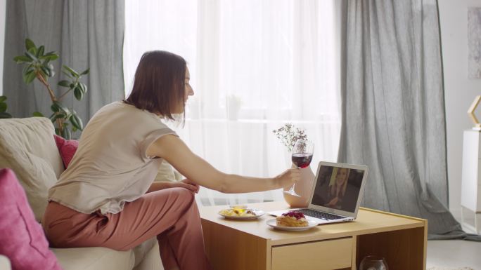 在笔记本电脑屏幕上与网友碰杯红酒的女人