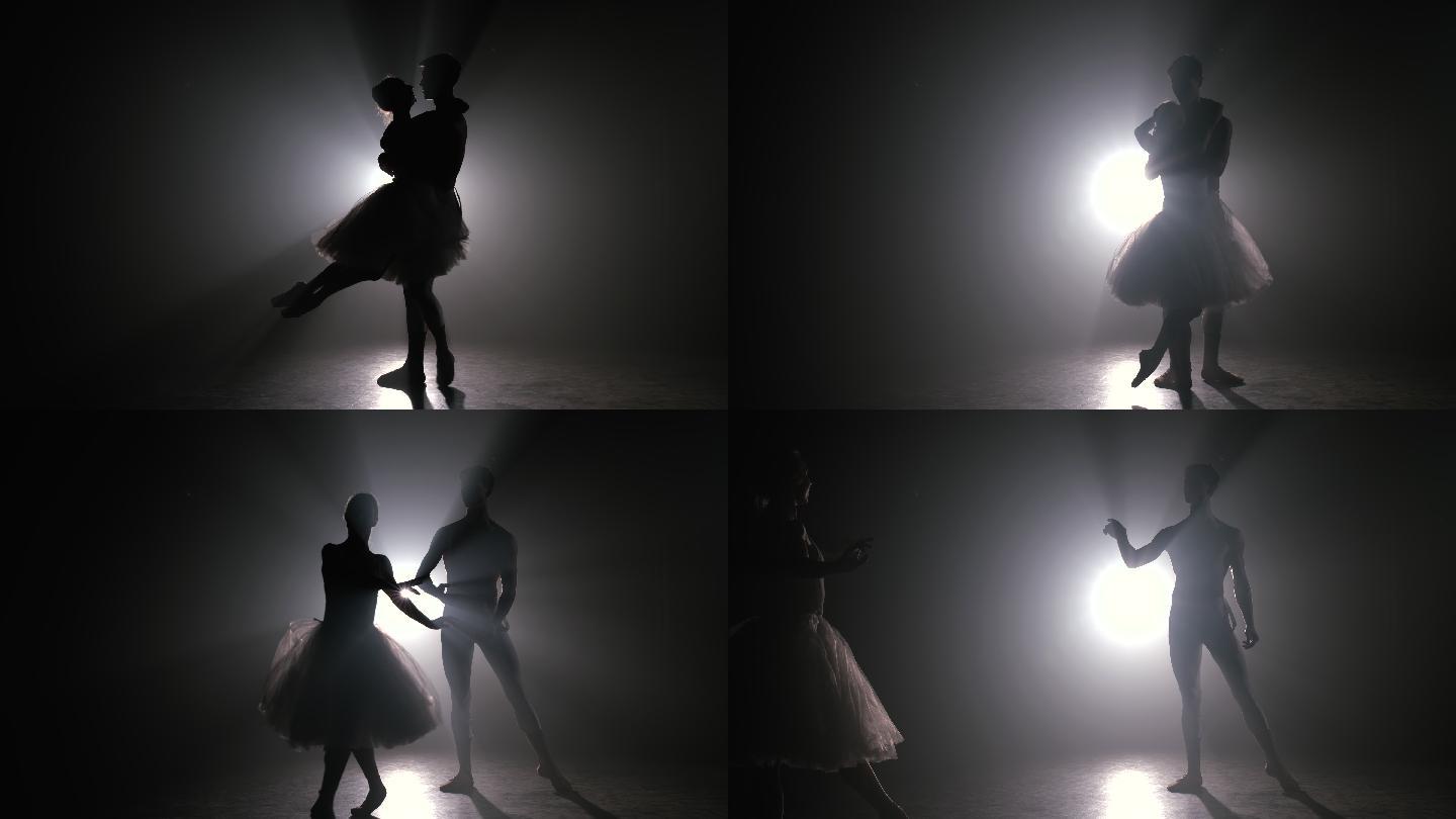一对芭蕾舞演员在黑暗的舞台上练习动作。