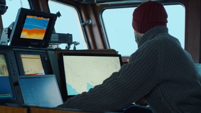 商业渔船的船长，在他的船舱里处理海图。