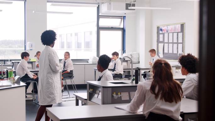 在科学课上，教师教坐在工作台上的学生