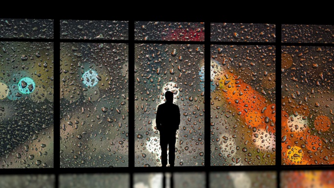 孤独的男人站在雨滴背景上的窗边