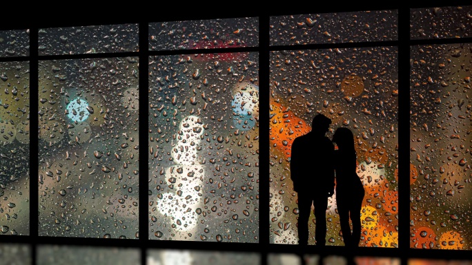 情侣站在雨滴背景的窗户前