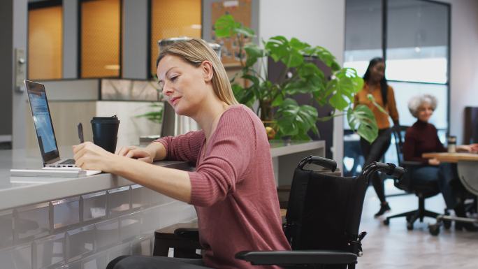 女商人在繁忙的现代办公室里用笔记本电脑工作