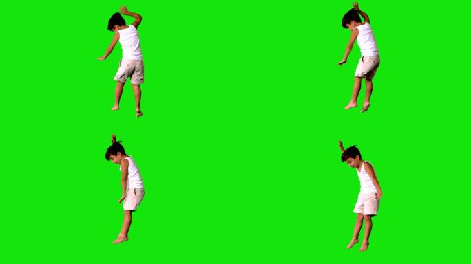 快乐的小男孩在绿色屏幕上跳跃和旋转