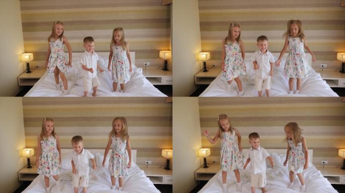 两个双胞胎女孩和一个小男孩跳到酒店房间的床上