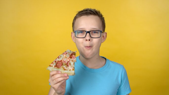 戴眼镜的男孩正在享用披萨