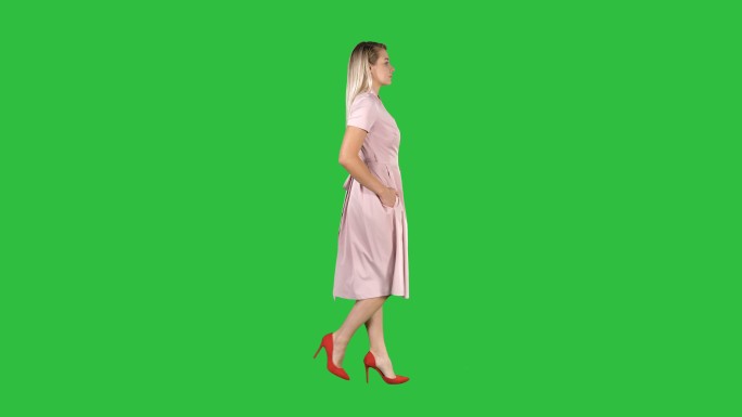 穿着粉色衣服在绿色屏幕上行走的年轻女孩