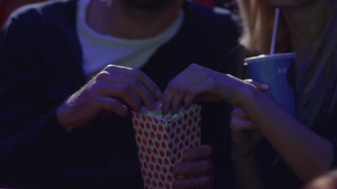 一对幸福的年轻情侣手牵手在电影院看电影