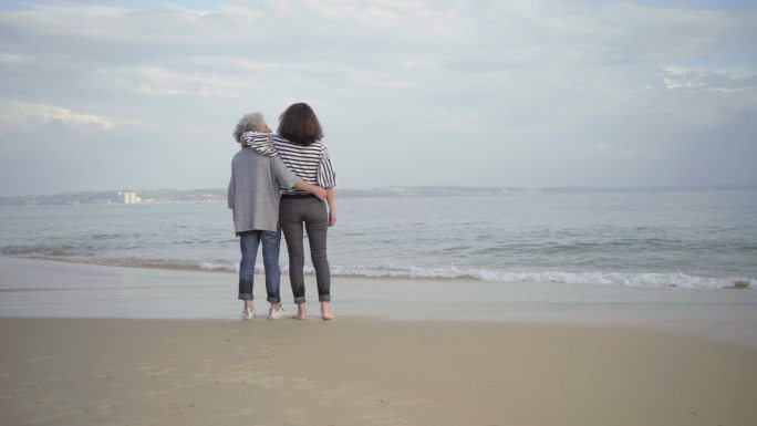两个微笑的女人在沙滩上拥抱