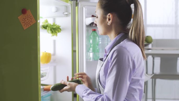 从冰箱里拿新鲜蔬菜的女人
