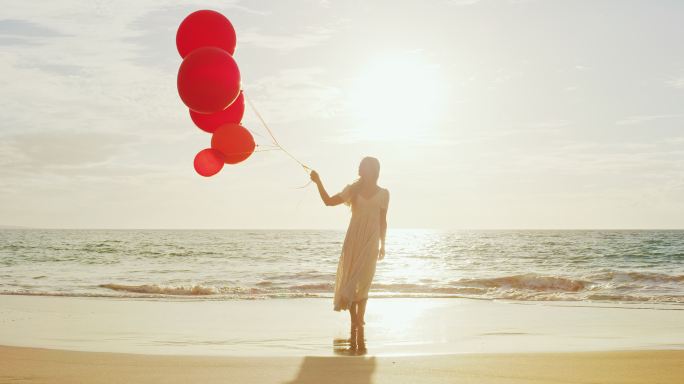 海滩上拿着气球的女人