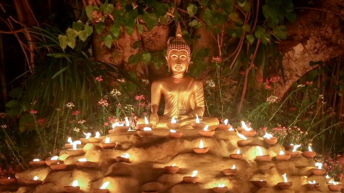 泰国清迈菩提树下点燃蜡烛的佛像