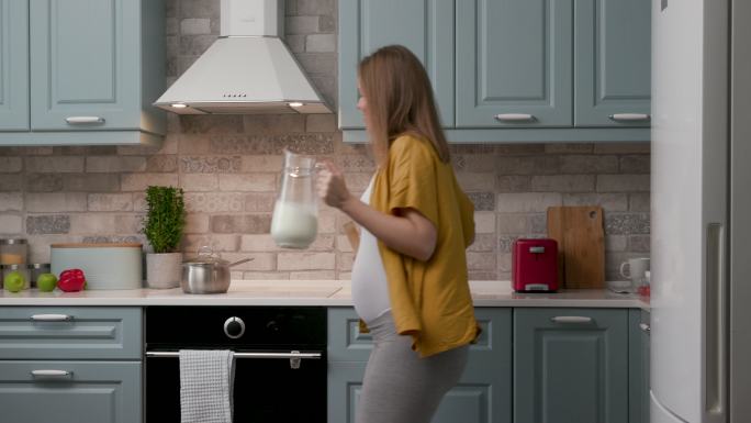 快乐的怀孕20多岁的妈妈在厨房跳舞