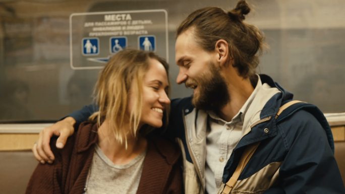 年轻漂亮的男人和女人坐在地铁车厢里聊天。