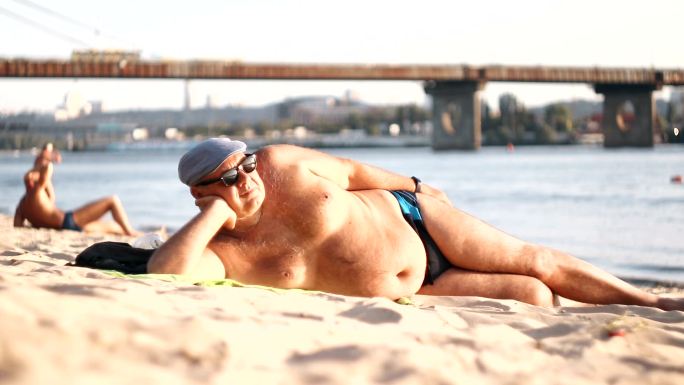 大腹便便的男人正在海滩上休息