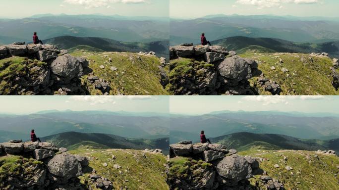 女子坐在山顶，眺望远方美丽的山脉。