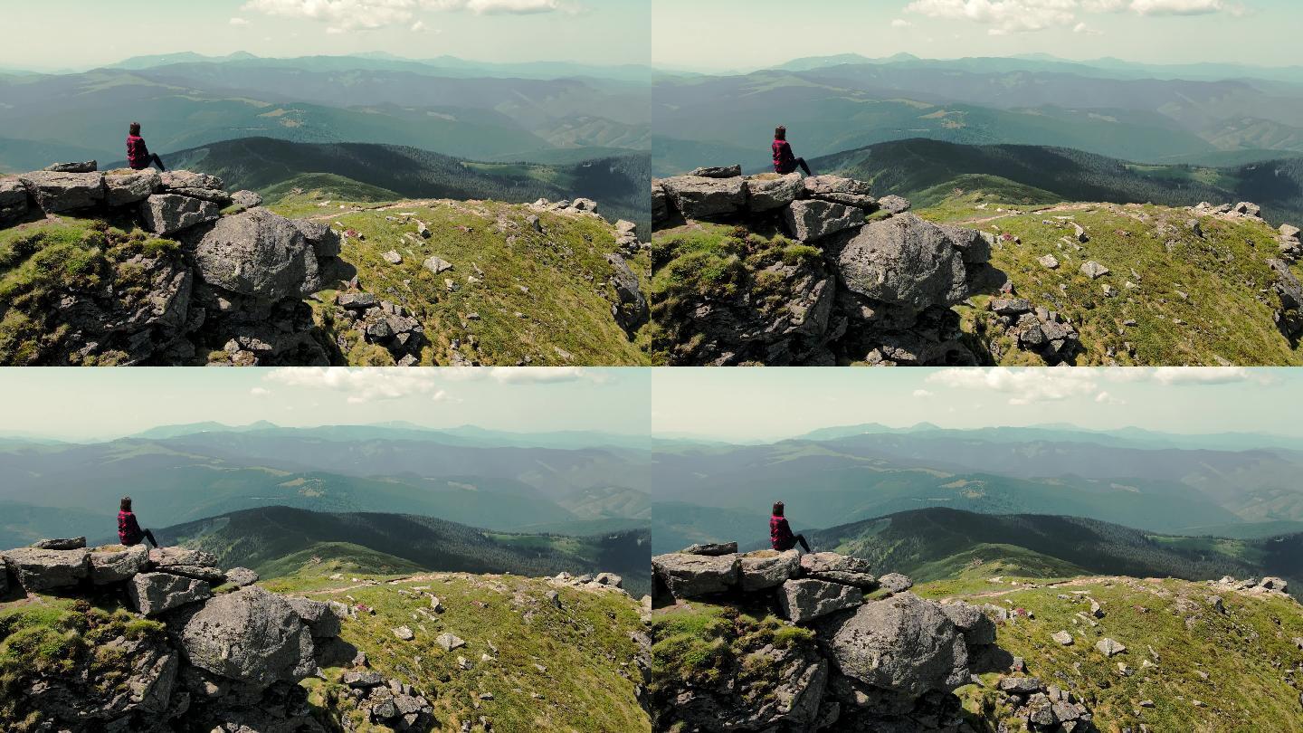 女子坐在山顶，眺望远方美丽的山脉。