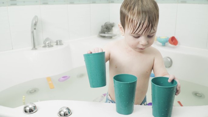 浴室里的小男孩在用杯子玩水